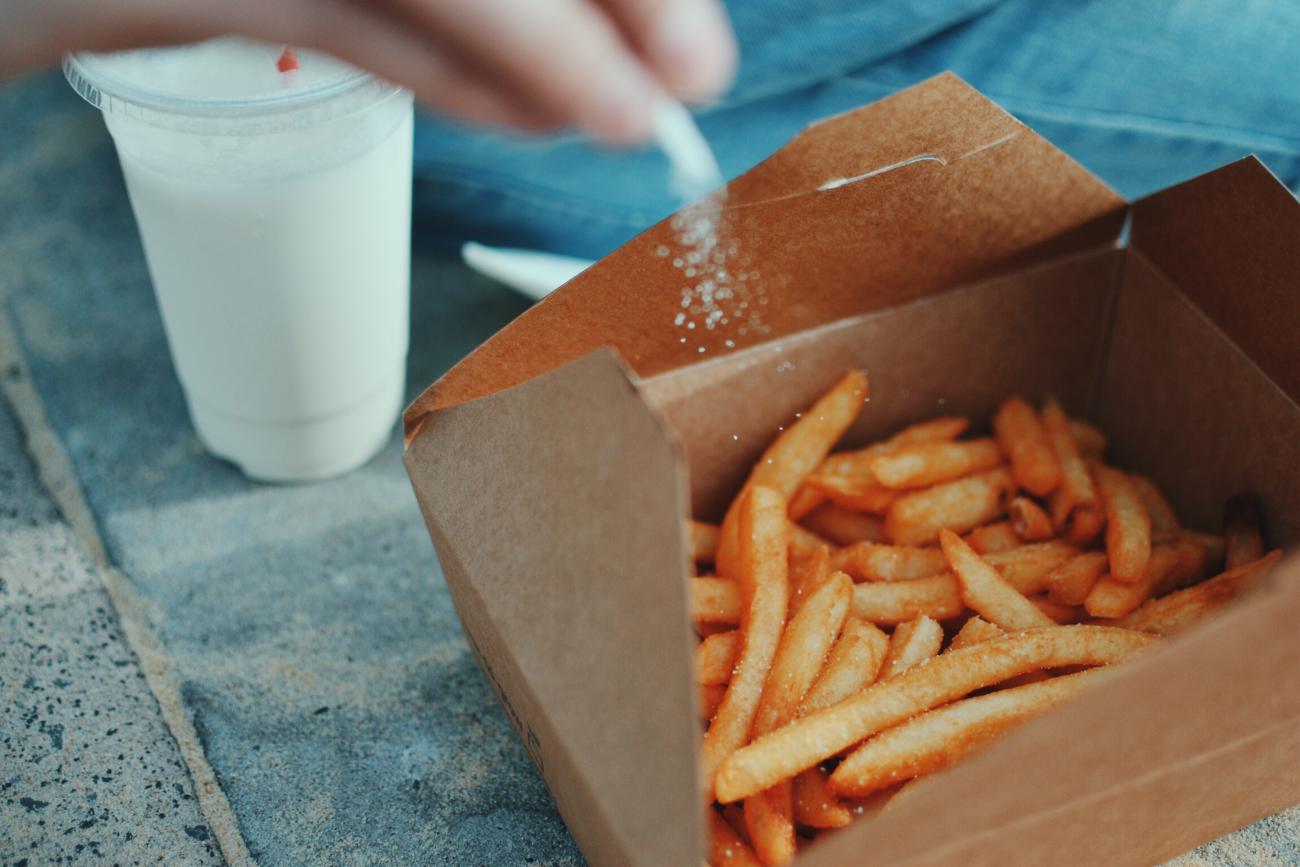 Iemand strooit zout over frieten in doosje. – Van Geloven geeft tips over je afhaalmenu