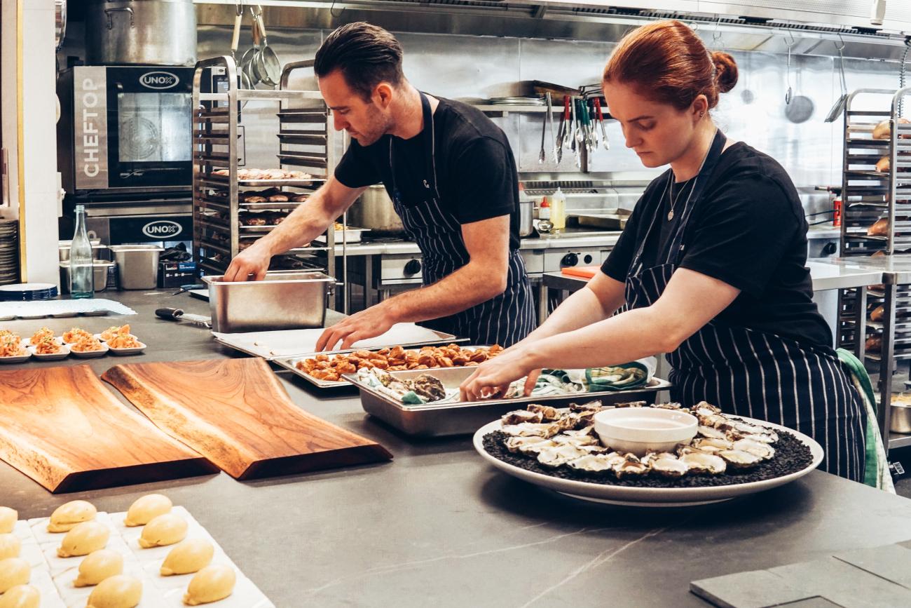 Image de 2 personnes en cuisine – Les conseils de Van Geloven pour préparer votre menu à enlever